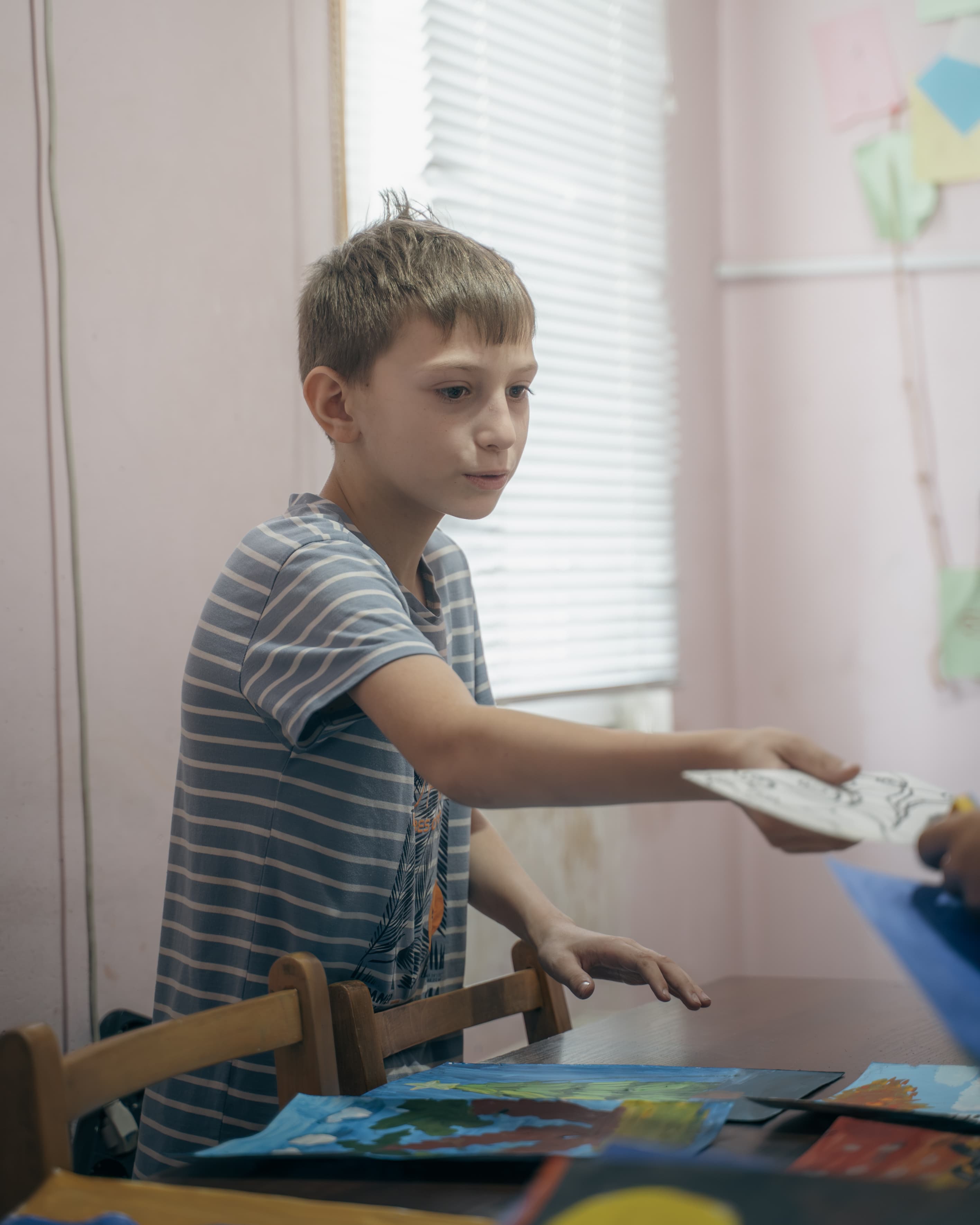 A boy handing over a drawing at Society Biliki
