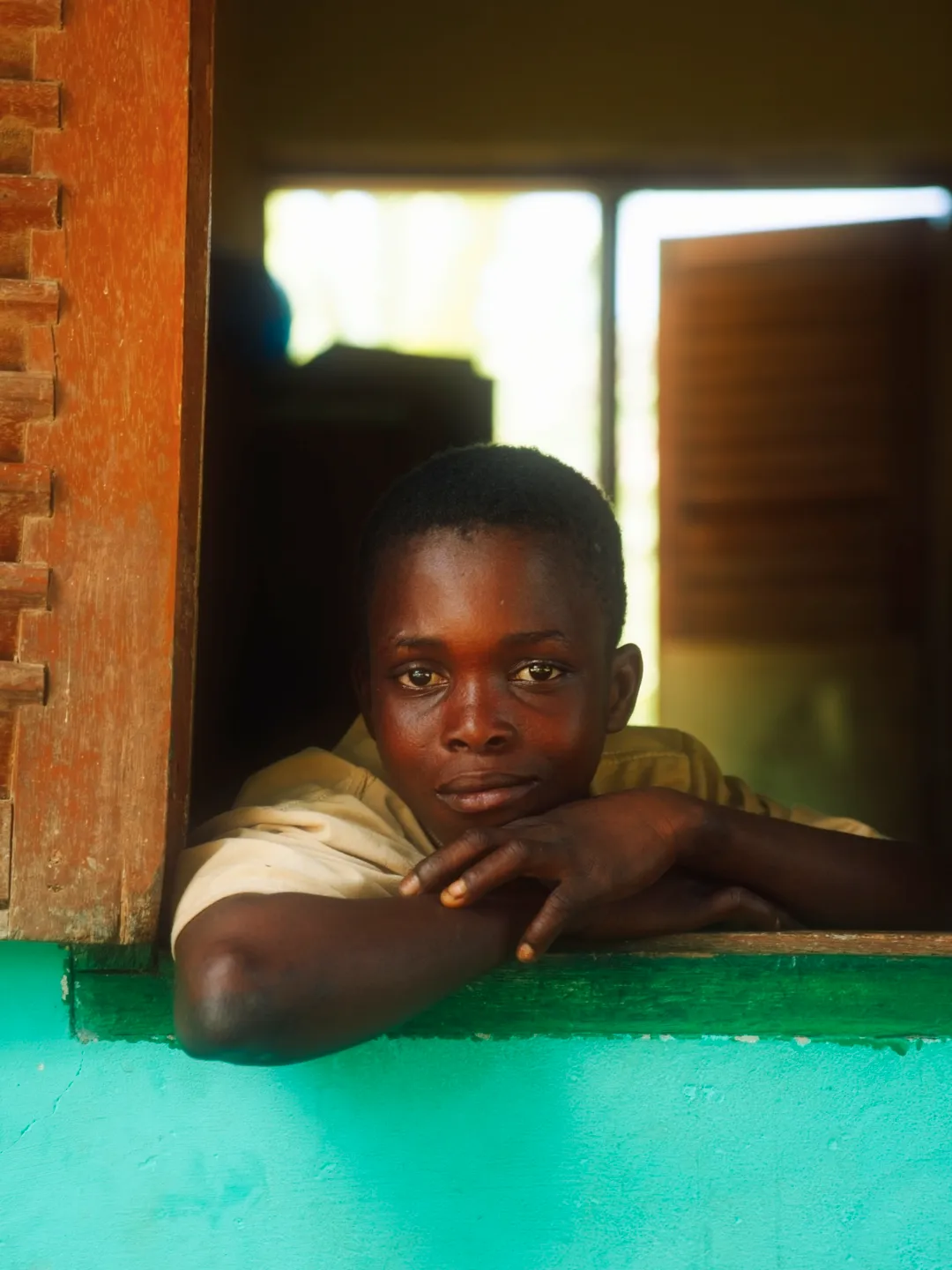 A boy leaning out of a green window frame